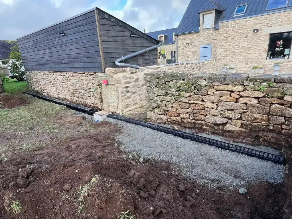 Caniveau de drainage des eaux pluviales le long d'un mur en pierre sèche, gestion des eaux en Finistère Sud