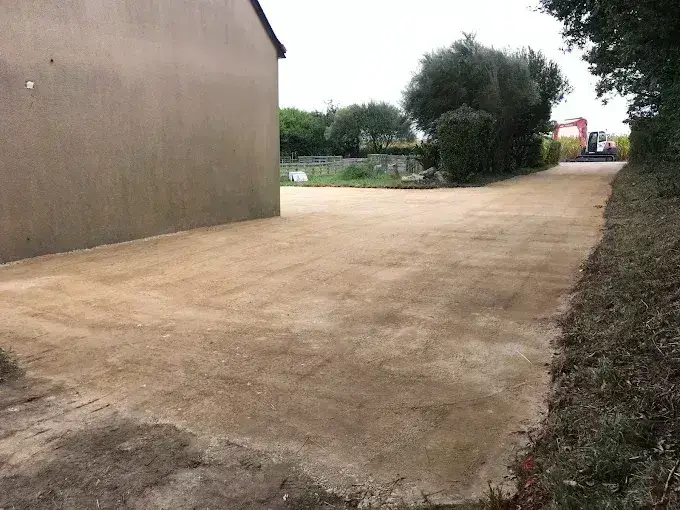 Cour d'accès en grave compactée le long d'un bâtiment, empierrement en Finistère Sud